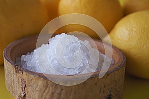 salt in a bowl and lemon on black yellow background