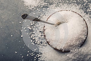 Salt. Coarse grained sea salt on granite - concrete stone background with vintage spoon and wooden bowl