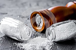 Salt in glass bottle with saltcellar on black stone table background