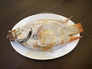 Salt-grilled ruby â€‹â€‹fish placed on a white plastic plate