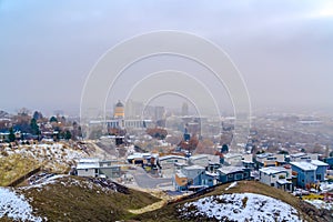 Salt Lake City downtown against cloudy sky viewed from a snowy hill in winter