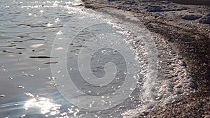 Salt lake, salt crystals. Salt water waves crash onto the shore in the self-precipitating salt of a salt lake.