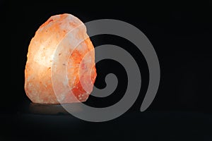 Salt lamp isolated against a black background. Mindfulness concept and esoterism. Empty copy space
