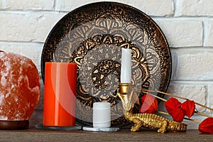 A salt lamp, a metallized African plate, an aromatic orange candle and other decorative and souvenir items on the shelf