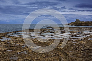 Salt pans, square pools on the northern coast of the island of Gozo in the Mediterranean Sea - salt extraction, sea salt