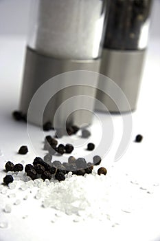 Salt and pepper corns, mills in background.