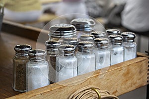 Salt and pepper rows at a restaurant ready to be placed on empty tables for dining customers