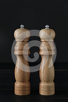 Salt and pepper shakers on black wooden table, closeup