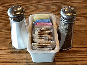 Salt and pepper shakers with a container of sugar and sugar substitute