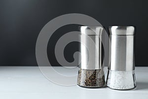 Salt and pepper shakers on white table, space for text