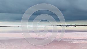 Salt pink lake reflective mirror with epic clouds