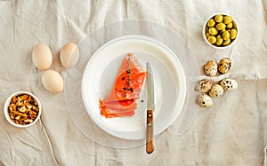 Salt Salmom with quail eggs, nuts and olive on a white linen tablecloth background. Top view. Keto diet concept. Ketogenic diet