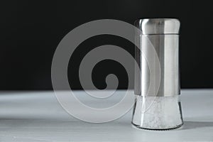 Salt shaker on white table, closeup. Space for text