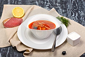 salt soup with meat and sausages, tomatoes and olives, lemon in restaurant serving