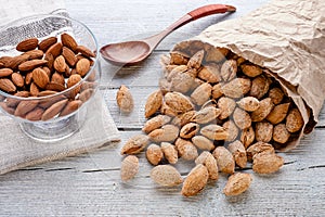 salted almonds in shell in paper bag on white wooden background