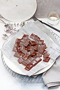 Salted caramel candies cut into square pieces, top view over grey baking paper