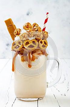 Salted caramel indulgent exreme milkshakes with brezel waffles, popcorn and whipped cream. Crazy freakshake trend