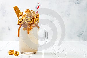 Salted caramel indulgent extreme milkshakes with brezel waffles, popcorn and whipped cream. Crazy freakshake food trend.