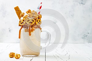 Salted caramel indulgent extreme milkshakes with brezel waffles, popcorn and whipped cream. Crazy freakshake food trend. photo