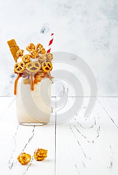Salted caramel indulgent extreme milkshakes with brezel waffles, popcorn and whipped cream. Crazy freakshake trend
