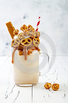 Salted caramel indulgent extreme milkshakes with brezel waffles, popcorn and whipped cream. Crazy freakshake trend