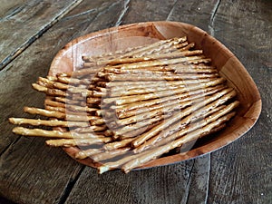 Salted chopsticks on a wooden plate. Deliciuse snack for a beer on the wooden table of old style. Food of breack time. photo