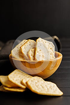 Salted Crackers in bowl Against a Dark Background