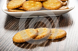 Salted crackers in plate on background, three cookies on table