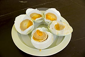 a salted duck egg telur asinserved in white plate isolated on wood backgrounds