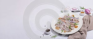 Salted herring with dijon mustard, dill and red onion rings on white stone background