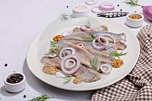 Salted herring with dijon mustard, dill and red onion rings on white stone background