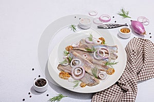 Salted herring with dijon mustard, dill and red onion rings on white stone background