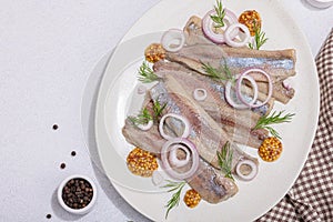 Salted herring with dijon mustard, dill and red onion rings on white stone background