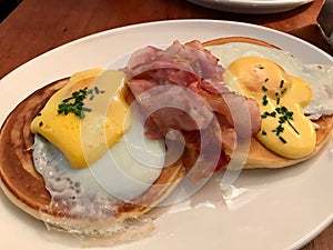 Salted Pancakes with Hollandaise Suace, Eggs and Crispy Bacon for Breakfast. Salty Organic Fast Food served at restaurant.