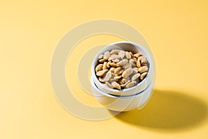Salted peanuts in a white bowl on a delt background in hard light. Healthy modern vegetarian food
