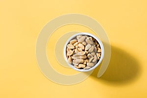 Salted peanuts in a white bowl on a delt background in hard light. Healthy modern vegetarian food. Top view
