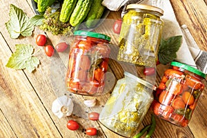 Salted pickled cucumbers and tomatoes preserved canned in glass jar.