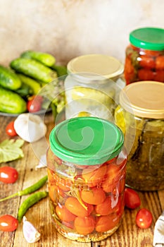 Salted pickled cucumbers and tomatoes preserved canned in glass jar.