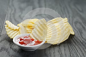 Salted potato ships with sauce on old wooden table