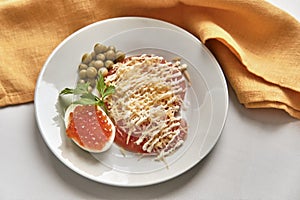 Salted red fish caviar on half of boiled chicken egg, slices of fresh red tomato under grated hard cheese