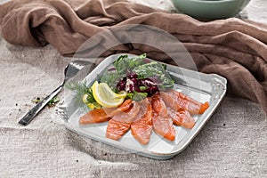 Salted salmon with salad and lemon on white plate on the table