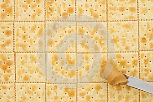 Saltine crackers background with knife full of peanut butter photo