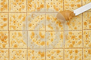 Saltine crackers background with knife full of peanut butter photo