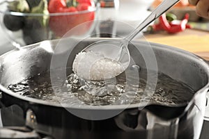 Salting boiling water in pot on stove