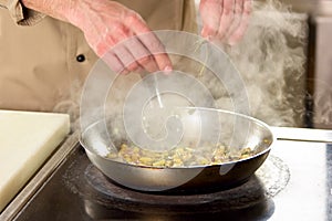 Salting steaming dish on stove.