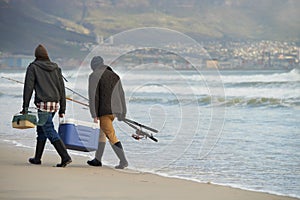 Saltwater fishing Man vs Sea. Full length shot of two young men fishing at the ocean in the early morning.