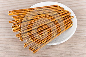 Salty bread sticks in white glass saucer on table