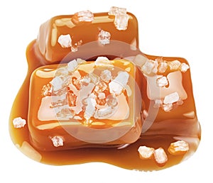Salty caramel candies in milk caramel sauce with salt crystals isolated on white background
