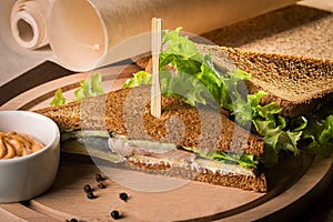 Salty fish sandwich with frash salad on round wooden board