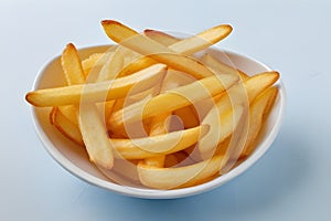 Salty French fries in a white bowl on a light background. Fast food concept.